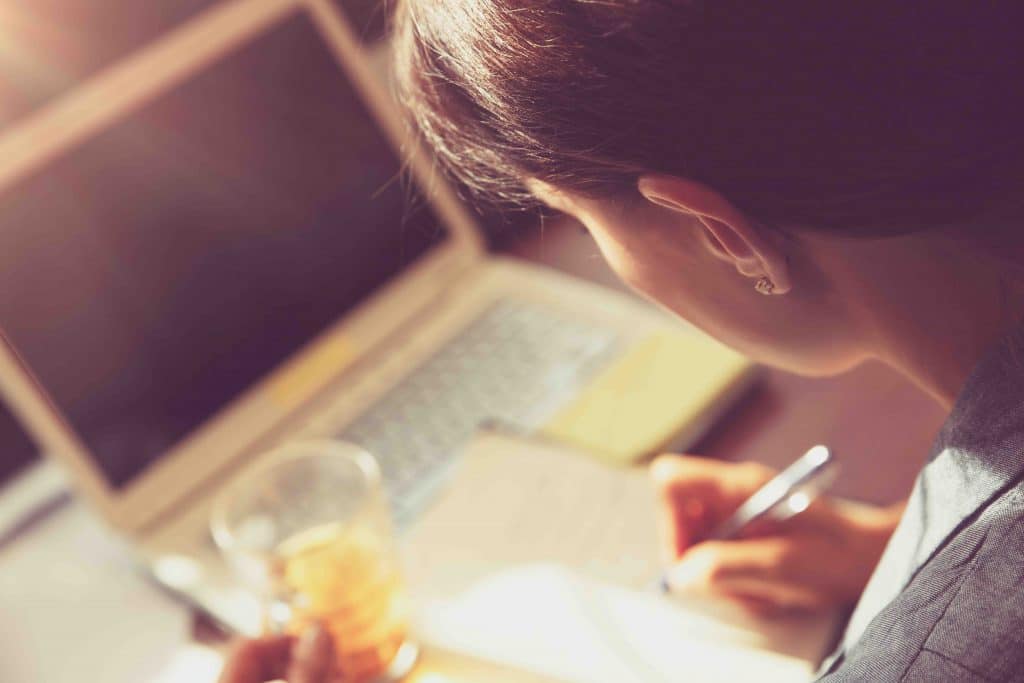 Business woman at work Business woman at work, back side of a woman writing something and drinking tea, working in the office, young successful people concept